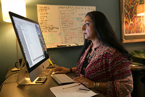 A woman reads information on her desktop monitor screen